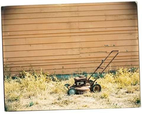 Rusted lawnmower against a wall